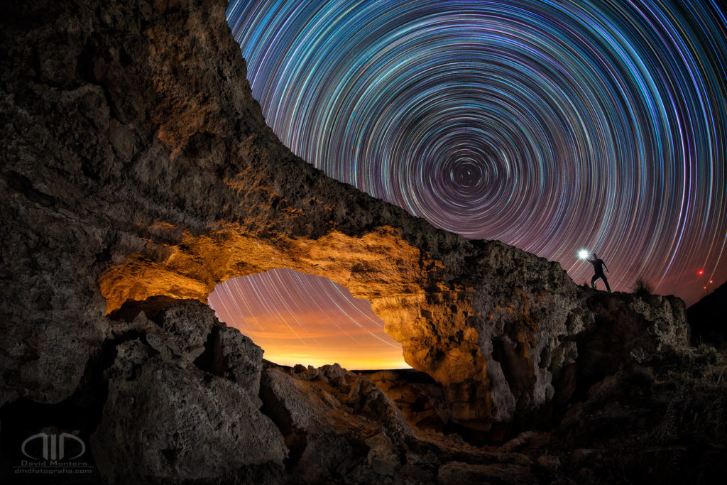 Circumpolar trazas de estrellas startrails sobre un arco de piedra natural. Fotografía nocturna